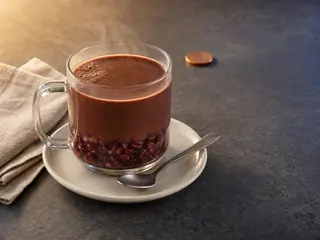Taza transparente de chocolate caliente sobre una capa de frijoles adzuki dulces