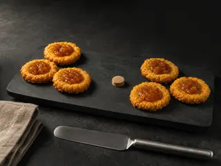 Golden cheddar thumbprint crackers filled with amber mango chutney on a stoneware board