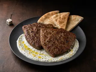 Kafta de carne em formato de escudo com molho de iogurte, tahine e limão e pão sírio integral