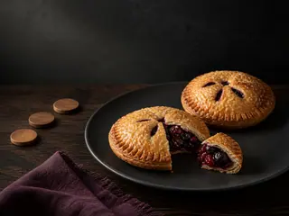 Empanadita redonda de frutos rojos con hojaldre azucarado y relleno espeso morado rojizo