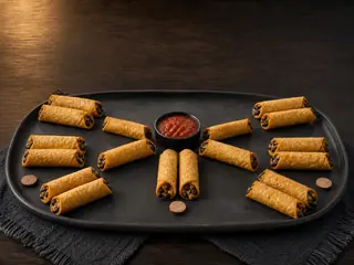 Taquitos assados de feijão-preto dispostos em rodadas de torneio ao redor de uma tigela de salsa