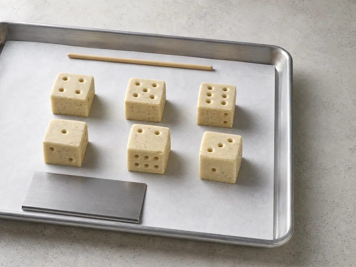Six unbaked cardamom shortbread cubes with clean recessed pip patterns for a two-serving scaled batch