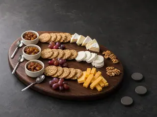 Three-route cheese board with apple-onion chutney, crackers, grapes, and walnuts