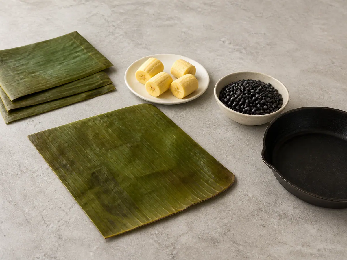 Softened banana leaves beside four banana pieces and drained cooked black beans