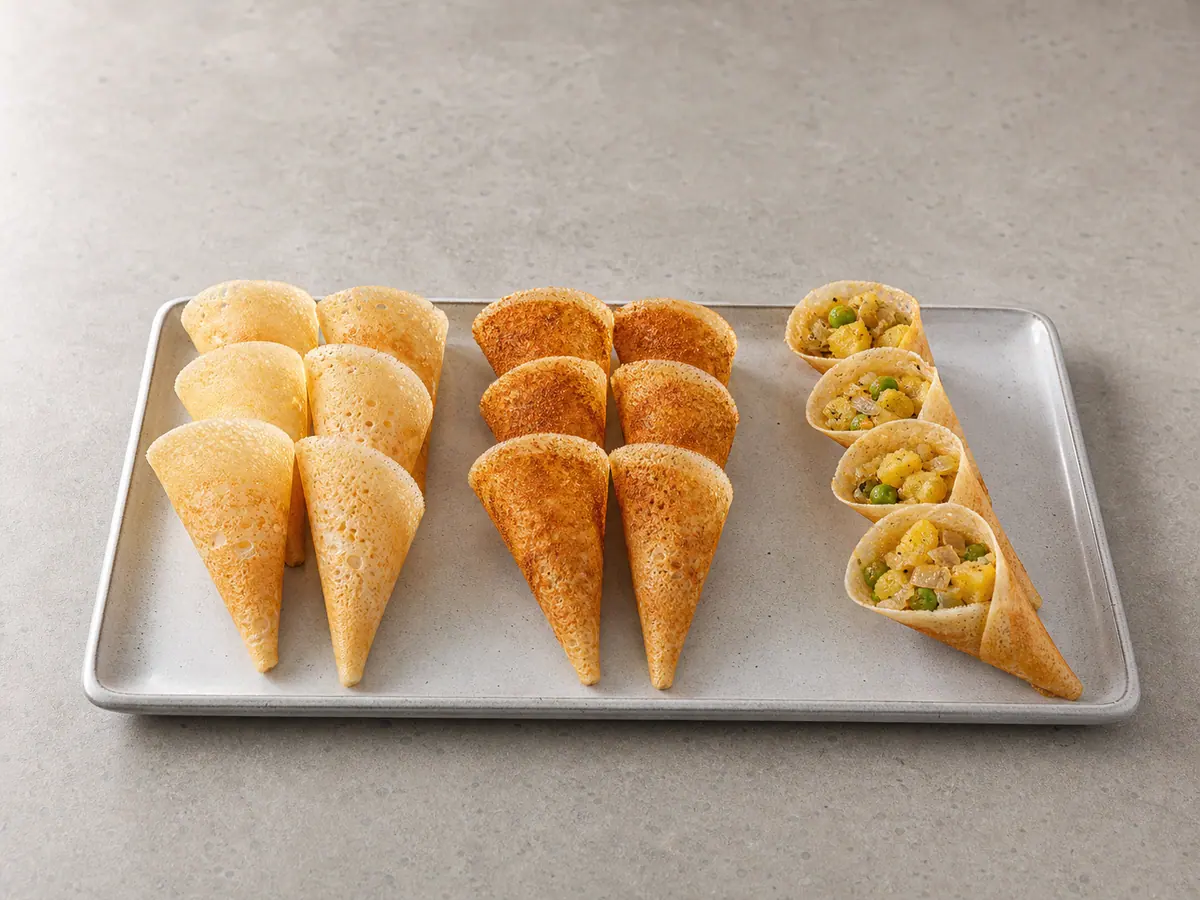 Plain, podi-brushed, and potato-pea-filled dosa cones arranged seam-side down