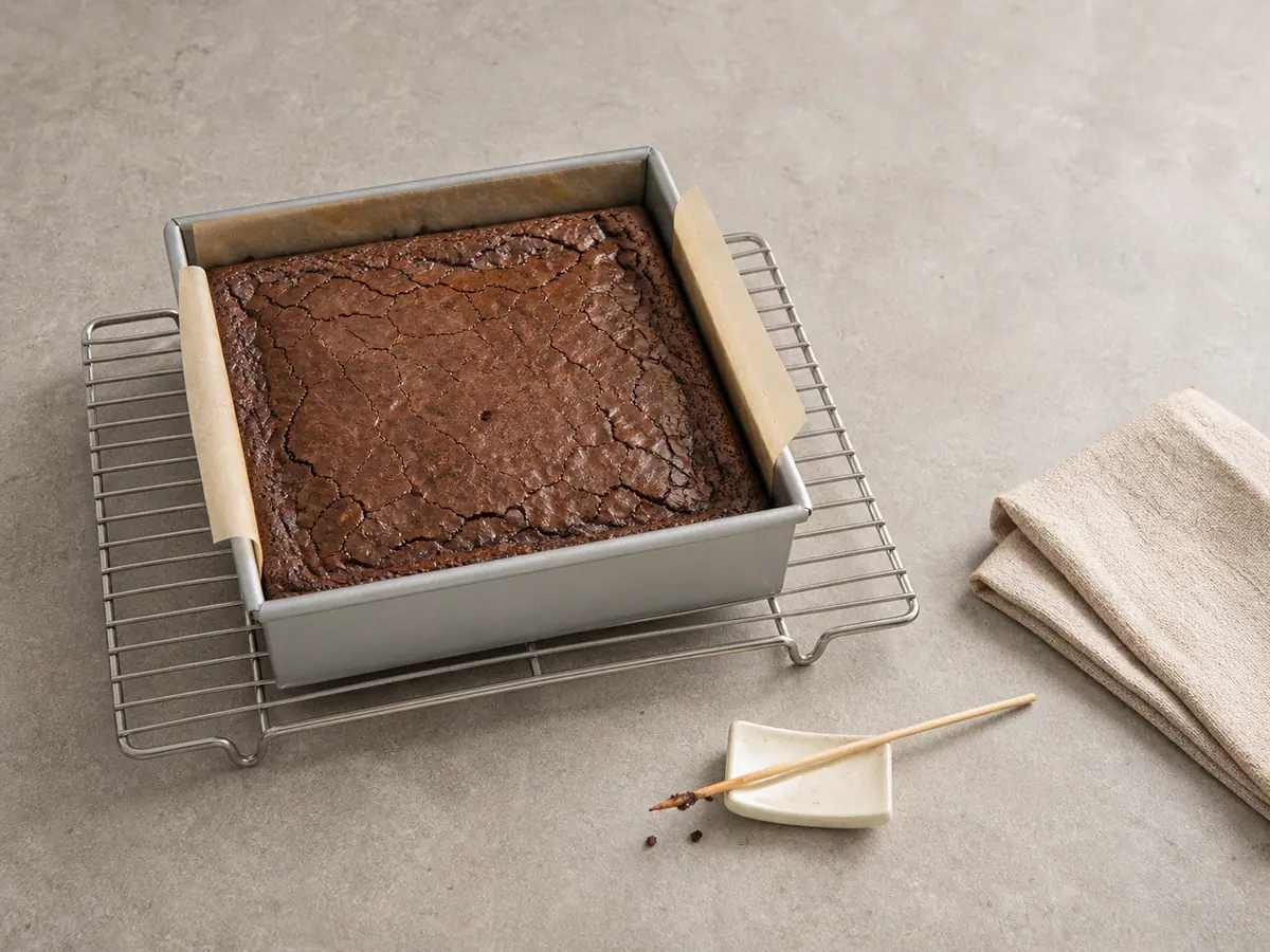 Brownie entero con relleno oculto completamente horneado, con bordes firmes y migas húmedas en un palillo