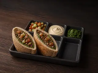 Two lentil pita pockets in a dark six-compartment serving tray