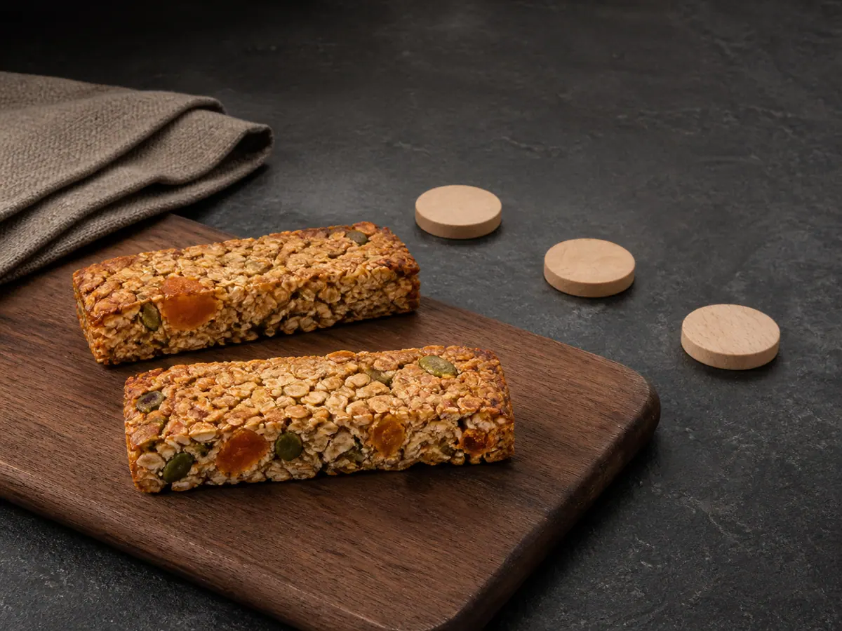 Two apricot oat slice bars with pumpkin seeds beside tabletop campaign tokens