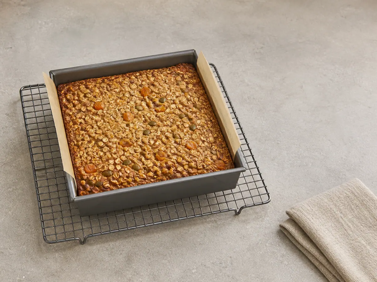 Baked apricot oat slice in a lined pan with golden edges and a set centre