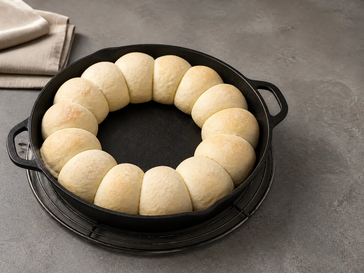 Pãezinhos de pretzel claros e firmes, pré-assados em uma coroa na frigideira, com o centro vazio