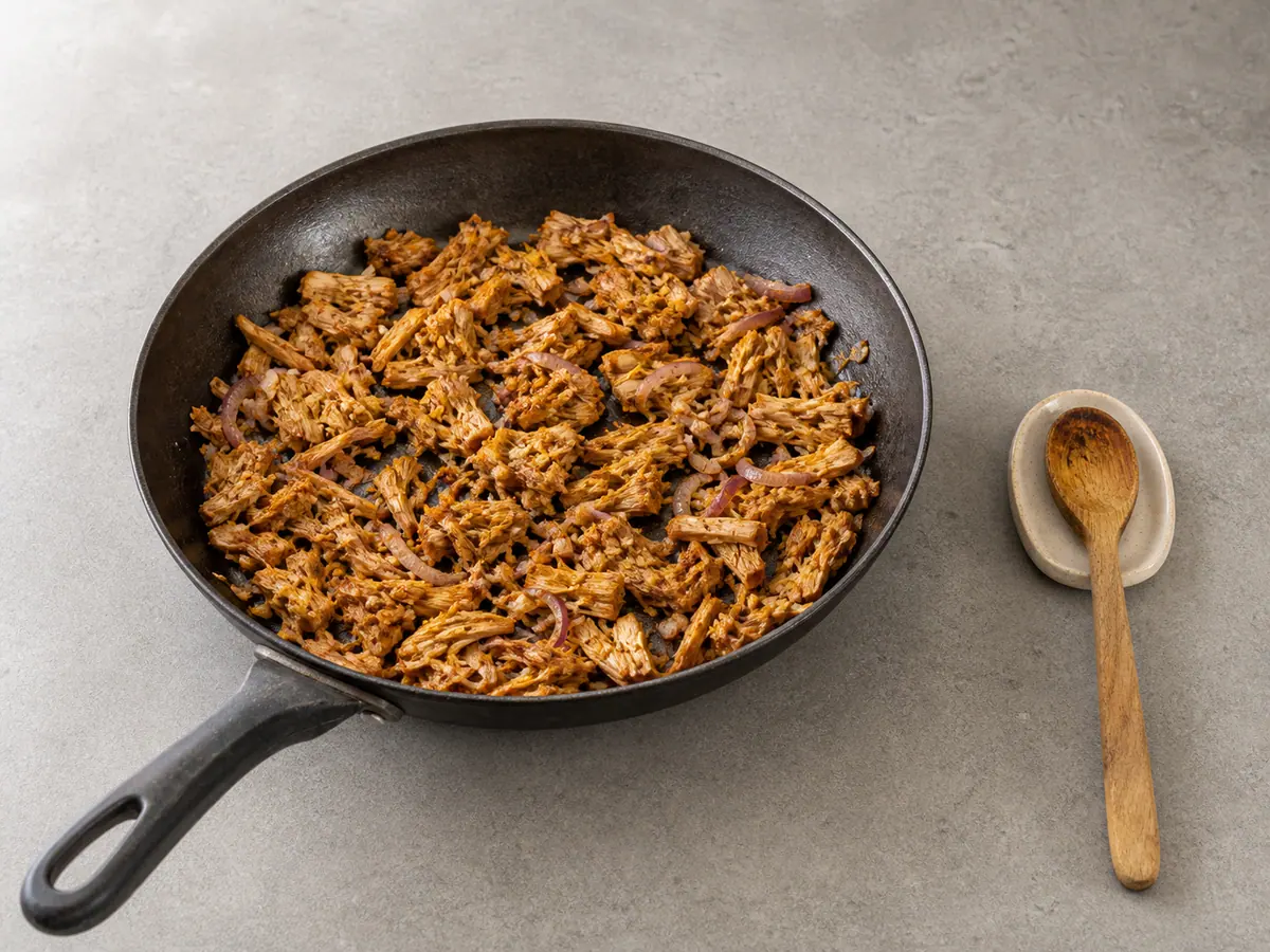 Pulled jackfruit browned with onion and spices before sauce is added
