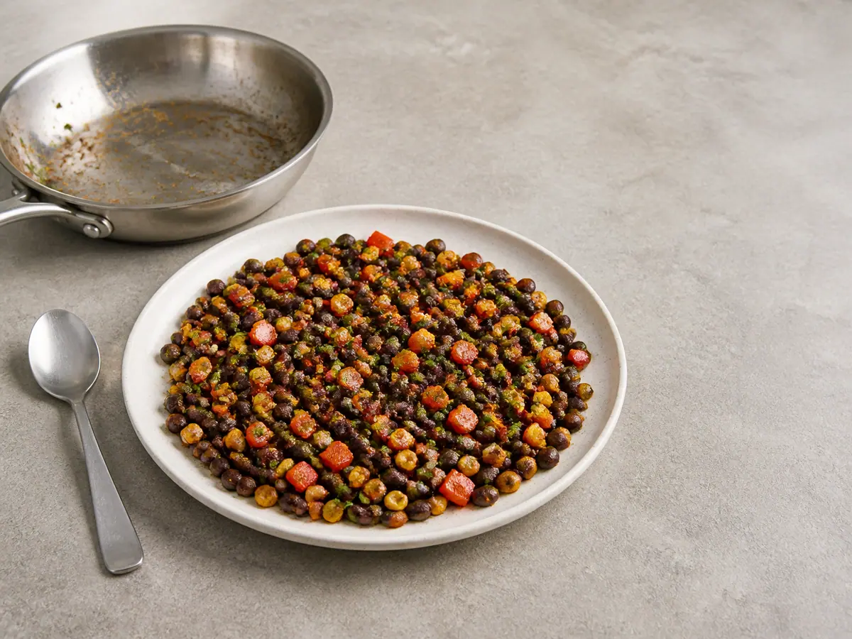 Dry black bean, corn, red pepper, scallion, cilantro, and lime filling spread on a plate until warm