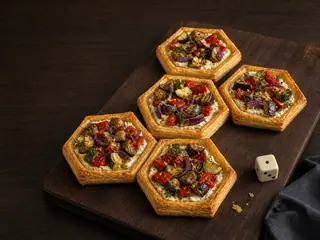 Cinco tartinhas hexagonais de legumes assados dispostas como uma rota ramificada sobre uma tábua escura
