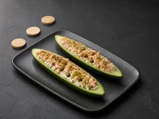 Two smoked trout cucumber boats arranged in a staggered route on a dark platter