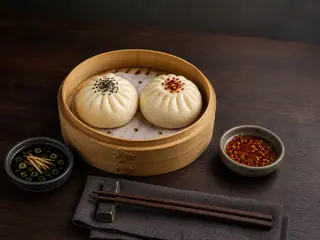 Canasta vaporera de bambú con dos bao de hongos y tofu y dos salsas para mojar de sabores contrastantes