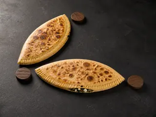 Two golden spinach-and-feta stuffed flatbreads arranged as diverging skill-tree branches on dark slate