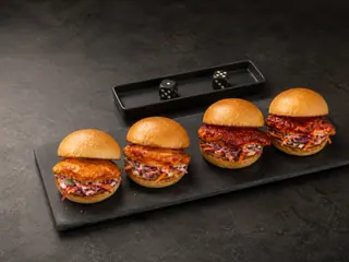 Four harissa chicken sliders arranged in gentler and hotter rows with red cabbage slaw